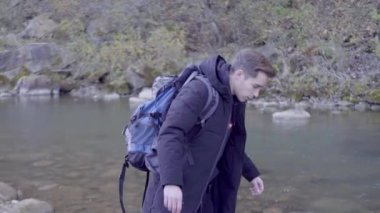 Kederli bir şekilde seyahat eden turist, macera arayışında, nehrin kenarında, ormanın içinde, dağın zirvesine doğru yürüyor.