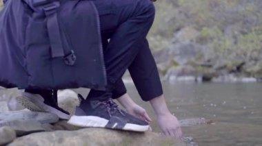 Kederli bir şekilde seyahat eden turist, macera arayışında, nehrin kenarında, ormanın içinde, dağın zirvesine doğru yürüyor.