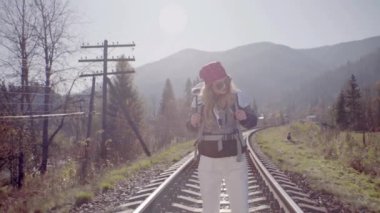 Kız raylarda yürüyor, yüksek dağlarda, bir trende.