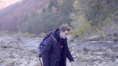 Kederli bir şekilde seyahat eden turist, macera arayışında, nehrin kenarında, ormanın içinde, dağın zirvesine doğru yürüyor.