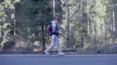 Kederli bir şekilde seyahat eden turist kız, macera arayışında, nehrin kenarında, ormanın içinden, dağın tepesine doğru yürüyor.