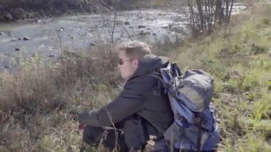 Kederli bir şekilde seyahat eden turist, macera arayışında, nehrin kenarında, ormanın içinde, dağın zirvesine doğru yürüyor.