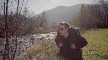 Kederli bir şekilde seyahat eden turist, macera arayışında, nehrin kenarında, ormanın içinde, dağın zirvesine doğru yürüyor.