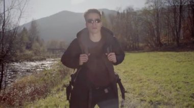 Kederli bir şekilde seyahat eden turist, macera arayışında, nehrin kenarında, ormanın içinde, dağın zirvesine doğru yürüyor.