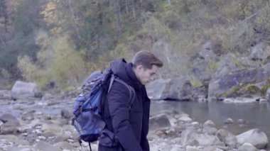 Kederli bir şekilde seyahat eden turist, macera arayışında, nehrin kenarında, ormanın içinde, dağın zirvesine doğru yürüyor.