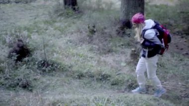 Kederli bir şekilde seyahat eden turist kız, macera arayışında, nehrin kenarında, ormanın içinden, dağın tepesine doğru yürüyor.