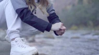 Kederli bir şekilde seyahat eden turist kız, macera arayışında, nehrin kenarında, ormanın içinden, dağın tepesine doğru yürüyor.