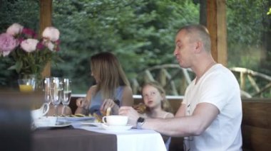 Aile yaz akşamı yemek yiyor. Masa, açık hava, çardak, kahvaltı.
