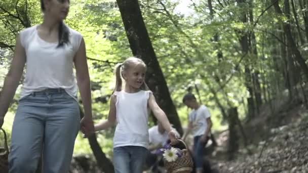 家庭踏上森林探险之旅 幸福的家庭的母亲 父亲和女儿手牵着手在针叶林中散步 父母给孩子们展示美丽的树 孩子们摘蘑菇 — 图库视频影像
