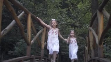 Mutlu kızlar köprünün üzerinden neşeli ebeveynlerine koşuyor. Anne ve babaların sevgi dolu kucaklamaları..