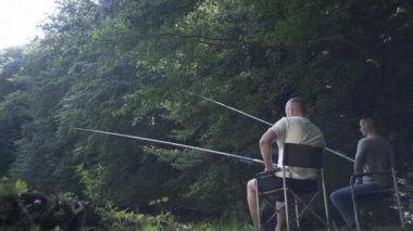 Neşeli arkadaşlar gülümsüyor, boş zamanların tadını çıkarıyor, balık tutuyor. Erkek arkadaşlar sohbet ediyor, balık tutma sürecinin tadını çıkarıyor, erkekler balık tutmaya çalışıyor..