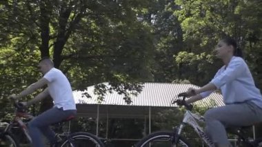 Aile parkta bisiklet sürüyor.