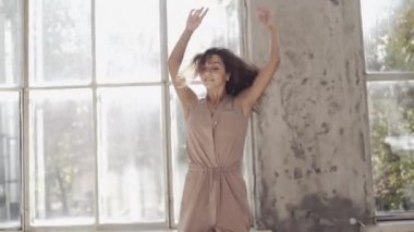 Uzun saçlı, modern dansçı kadın. Çağdaş serbest stil. Stüdyoda büyük camlı beyaz bir kız dans ediyor. Seksi kız dans hareketleri yapıyor..