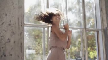 Uzun saçlı, modern dansçı kadın. Çağdaş serbest stil. Stüdyoda büyük camlı beyaz bir kız dans ediyor. Seksi kız dans hareketleri yapıyor..
