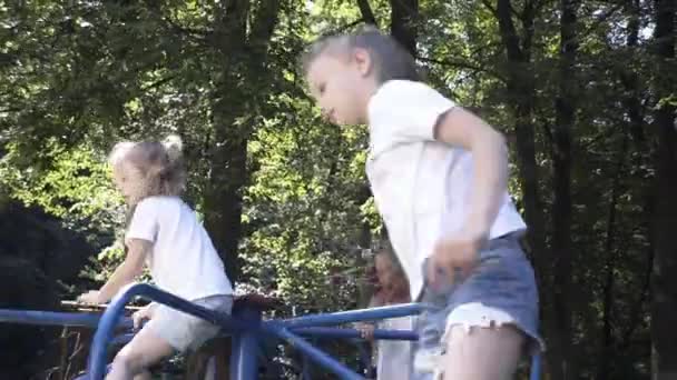 女の子はスイング 子供のスライド カルーセル 遊び場に乗っています — ストック動画