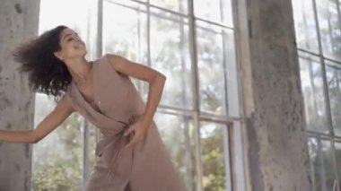 Uzun saçlı, modern dansçı kadın. Çağdaş serbest stil. Stüdyoda büyük camlı beyaz bir kız dans ediyor. Seksi kız dans hareketleri yapıyor..