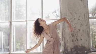 Uzun saçlı, modern dansçı kadın. Çağdaş serbest stil. Stüdyoda büyük camlı beyaz bir kız dans ediyor. Seksi kız dans hareketleri yapıyor..