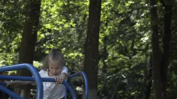 女の子はスイング 子供のスライド カルーセル 遊び場に乗っています — ストック動画