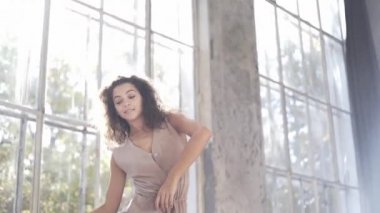 Uzun saçlı, modern dansçı kadın. Çağdaş serbest stil. Stüdyoda büyük camlı beyaz bir kız dans ediyor. Seksi kız dans hareketleri yapıyor..