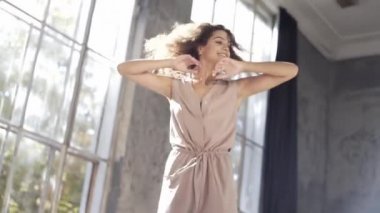 Uzun saçlı, modern dansçı kadın. Çağdaş serbest stil. Stüdyoda büyük camlı beyaz bir kız dans ediyor. Seksi kız dans hareketleri yapıyor..