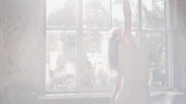 Uzun saçlı, modern dansçı kadın. Çağdaş serbest stil. Stüdyoda büyük camlı beyaz bir kız dans ediyor. Seksi kız dans hareketleri yapıyor..