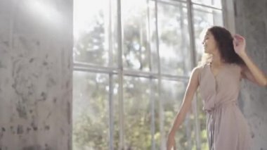Uzun saçlı, modern dansçı kadın. Çağdaş serbest stil. Stüdyoda büyük camlı beyaz bir kız dans ediyor. Seksi kız dans hareketleri yapıyor..
