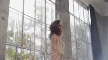 Uzun saçlı, modern dansçı kadın. Çağdaş serbest stil. Stüdyoda büyük camlı beyaz bir kız dans ediyor. Seksi kız dans hareketleri yapıyor..