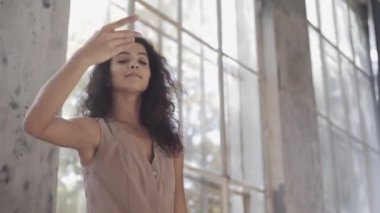 Uzun saçlı, modern dansçı kadın. Çağdaş serbest stil. Stüdyoda büyük camlı beyaz bir kız dans ediyor. Seksi kız dans hareketleri yapıyor..