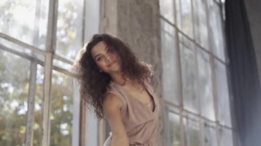 Uzun saçlı, modern dansçı kadın. Çağdaş serbest stil. Stüdyoda büyük camlı beyaz bir kız dans ediyor. Seksi kız dans hareketleri yapıyor..