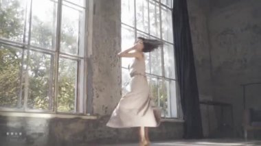 Uzun saçlı, modern dansçı kadın. Çağdaş serbest stil. Stüdyoda büyük camlı beyaz bir kız dans ediyor. Seksi kız dans hareketleri yapıyor..