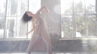 Uzun saçlı, modern dansçı kadın. Çağdaş serbest stil. Stüdyoda büyük camlı beyaz bir kız dans ediyor. Seksi kız dans hareketleri yapıyor..