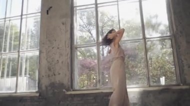 Uzun saçlı, modern dansçı kadın. Çağdaş serbest stil. Stüdyoda büyük camlı beyaz bir kız dans ediyor. Seksi kız dans hareketleri yapıyor..