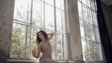 Uzun saçlı, modern dansçı kadın. Çağdaş serbest stil. Stüdyoda büyük camlı beyaz bir kız dans ediyor. Seksi kız dans hareketleri yapıyor..