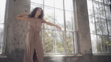 Uzun saçlı, modern dansçı kadın. Çağdaş serbest stil. Stüdyoda büyük camlı beyaz bir kız dans ediyor. Seksi kız dans hareketleri yapıyor..