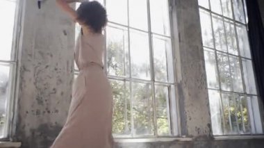 Uzun saçlı, modern dansçı kadın. Çağdaş serbest stil. Stüdyoda büyük camlı beyaz bir kız dans ediyor. Seksi kız dans hareketleri yapıyor..