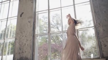 Uzun saçlı, modern dansçı kadın. Çağdaş serbest stil. Stüdyoda büyük camlı beyaz bir kız dans ediyor. Seksi kız dans hareketleri yapıyor..