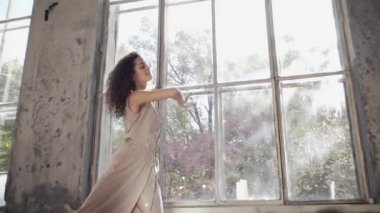 Uzun saçlı, modern dansçı kadın. Çağdaş serbest stil. Stüdyoda büyük camlı beyaz bir kız dans ediyor. Seksi kız dans hareketleri yapıyor..