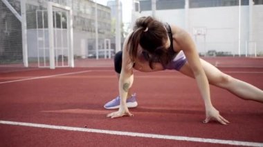 beautiful girl, gymnast, shows gymnastic tricks and fitness workout on the sports field / flattering girl, gymnast, performs sports exercises, stretching, sits and sits on the splits .