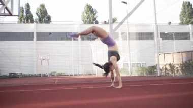 beautiful girl, gymnast, shows gymnastic tricks and fitness workout on the sports field / flattering girl, gymnast, performs sports exercises, stretching, sits and sits on the splits .