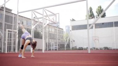 beautiful girl, gymnast, shows gymnastic tricks and fitness workout on the sports field / flattering girl, gymnast, performs sports exercises, stretching, sits and sits on the splits .