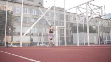 beautiful girl, gymnast, shows gymnastic tricks and fitness workout on the sports field / flattering girl, gymnast, performs sports exercises, stretching, sits and sits on the splits .