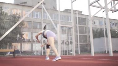 beautiful girl, gymnast, shows gymnastic tricks and fitness workout on the sports field / flattering girl, gymnast, performs sports exercises, stretching, sits and sits on the splits .