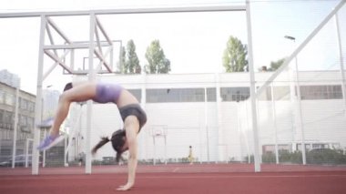 beautiful girl, gymnast, shows gymnastic tricks and fitness workout on the sports field / flattering girl, gymnast, performs sports exercises, stretching, sits and sits on the splits .