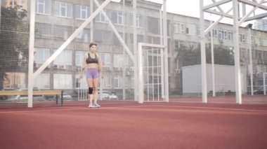 beautiful girl, gymnast, shows gymnastic tricks and fitness workout on the sports field / flattering girl, gymnast, performs sports exercises, stretching, sits and sits on the splits .