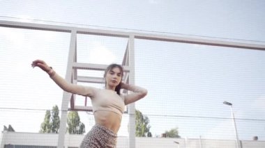 beautiful girl, gymnast, shows gymnastic tricks and fitness workout on the sports field / flattering girl, gymnast, performs sports exercises, stretching, sits and sits on the splits .