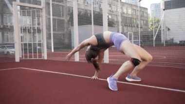 beautiful girl, gymnast, shows gymnastic tricks and fitness workout on the sports field / flattering girl, gymnast, performs sports exercises, stretching, sits and sits on the splits .