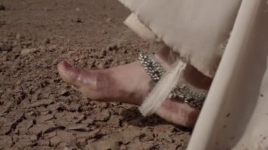 Bir kız Hindistan çölünde yürüyor, kutsal bir ateş taşıyor. Antik topraklar, Hint çölü, kuraklıktan ölen topraklar, kızıl toprak, hepsi çatlaklar içinde.