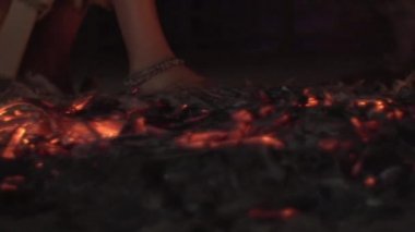 Çıplak ayaklı bir kadın kızgın kömürlerin üzerinde kararlı bir şekilde yürür. Çıplak ayaklı cesur kadın kızgın kömürlerin üzerinde koşar.. 
