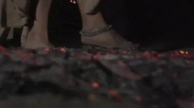 Çıplak ayaklı bir kadın kızgın kömürlerin üzerinde kararlı bir şekilde yürür. Çıplak ayaklı cesur kadın kızgın kömürlerin üzerinde koşar.. 