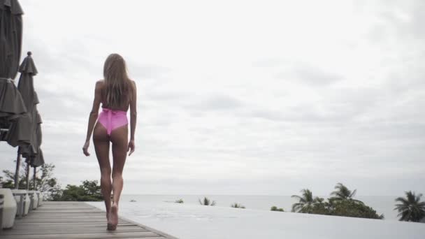 セクシーな女の子は非常に美しい姿で水着でプールの近くに行きます — ストック動画